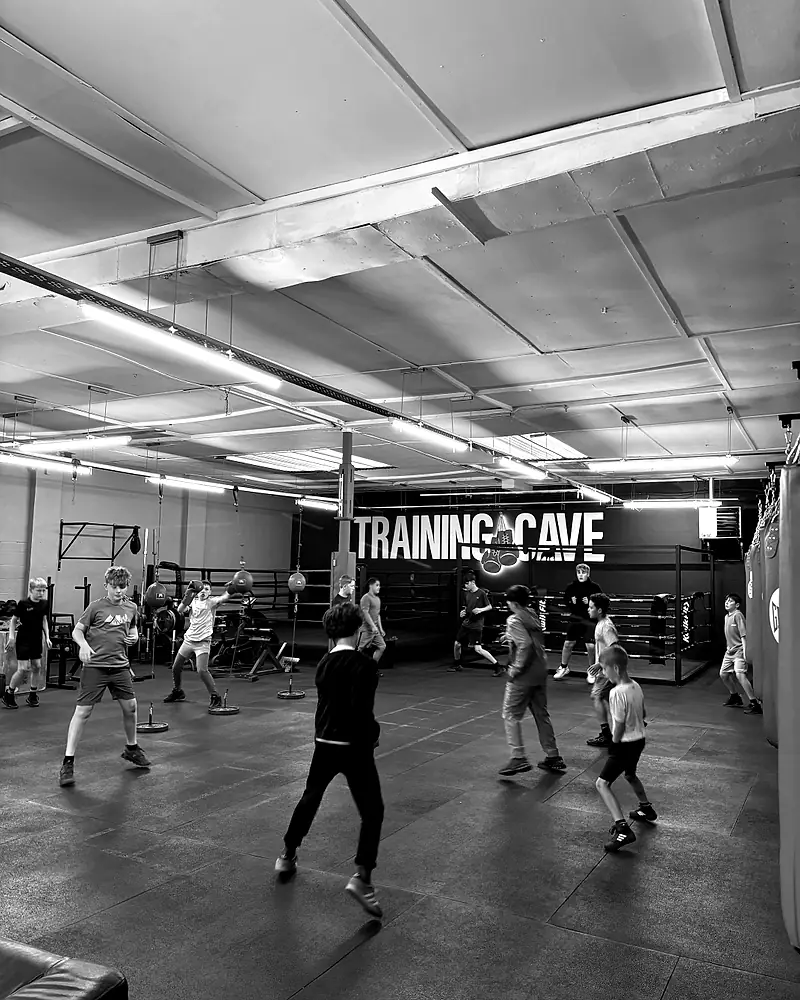 Trainingshalle mit Sandsäcken, mehrere Menschen trainieren.